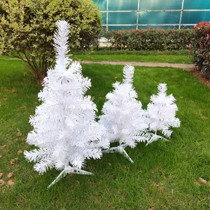 Close-up of three white mini artificial Christmas trees in different sizes on grass
