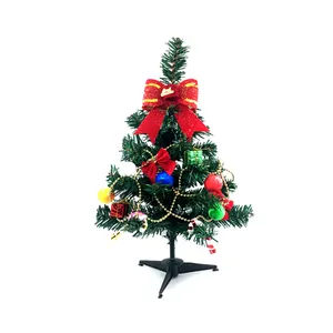 Small artificial Christmas tree with red bow and colorful ornaments on white background.