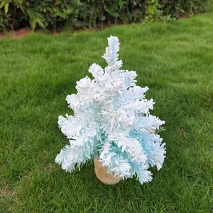 Vue détaillée d'un mini sapin de Noël bleu floqué avec effet neige sur l'herbe