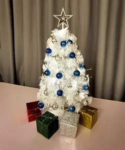 Close-up van een mini witte kerstboom versierd met blauwe en zilveren kerstballen