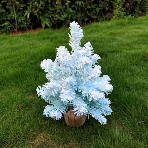 Vue détaillée d'un sapin de Noël floqué bleu clair avec une base en toile de jute.
