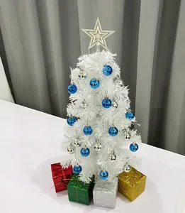 Gedetailleerd beeld van een kleine witte kunstkerstboom met blauwe ornamenten en kado.