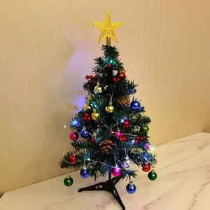 Mini desktop Christmas tree with colorful baubles and LED lights on a white surface.