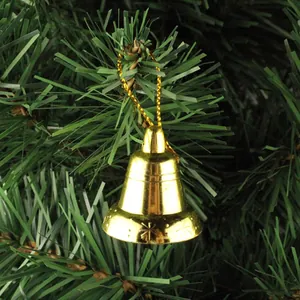 Close-up of a shiny golden Christmas bell ornament hanging on green pine needles
