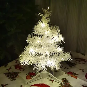 Close-up of mini white Christmas tree with warm LED lights for tabletop decor