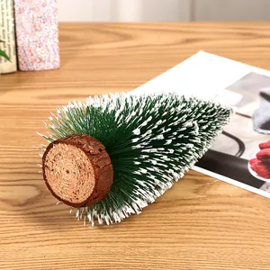 Close-up view of a mini snow-flocked Christmas tree with a rustic natural wooden base