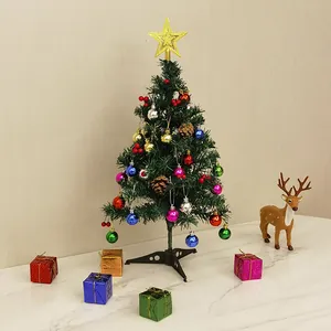 Small tabletop artificial Christmas tree with colorful ornaments and star topper