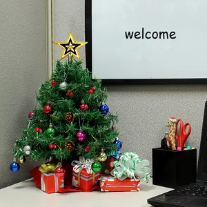 Decorated mini desktop Christmas tree set with colorful balls and star topper on office desk
