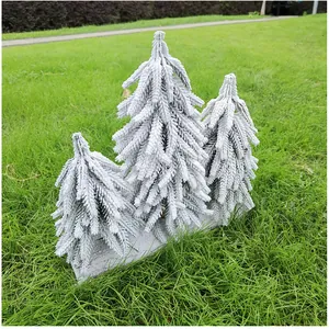 Detailansicht von drei kleinen weißen geflockten Zedern-Weihnachtsbäumen für die Tischdekoration