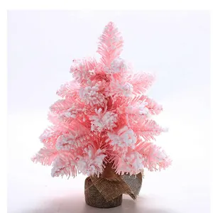 Vue détaillée d'un petit sapin de Noël rose floqué avec base en toile de jute.