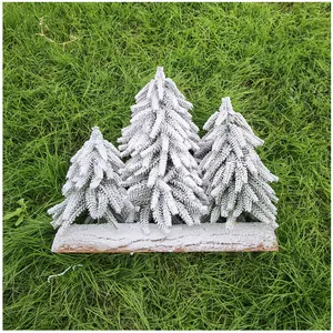 Detailansicht von drei mini beflockten Weihnachtsbäumen auf rustikalem Holzsockel