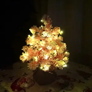 Gros plan d'un mini sapin de Noël rose floqué avec des lumières LED chaudes et base en toile