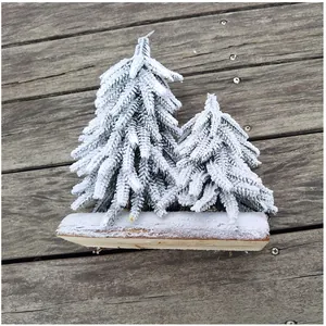 Detailansicht verschneiter Mini-Weihnachtsbäume auf einem rustikalen Holzsockel Dekor