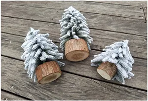 Detailansicht von drei mini beflockten Weihnachtsbäumen mit Holzsockel auf einer Terrasse