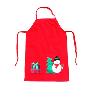 Vue détaillée du tablier de Noël rouge avec appliqués bonhomme de neige et sapin.