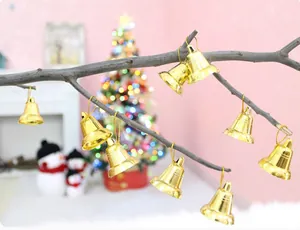 Nahaufnahme von glänzenden goldenen Weihnachtsglocken, die an einem Ast hängen