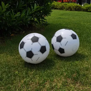 Close-up view of two inflatable soccer style beach balls resting on a lush green lawn