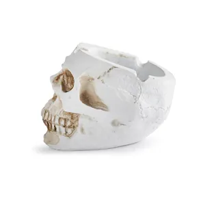 Detailed side view of a white resin skull-shaped ashtray with distressed bone texture.