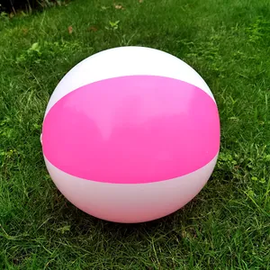 Detailed view of a pink and white inflatable beach ball resting on lush green grass.