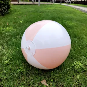 Detail of a 36cm pink and white striped inflatable beach ball on a lush green grass lawn