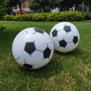 Two inflatable soccer balls with classic black and white pentagon pattern on grass.