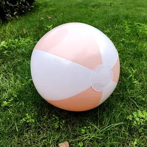 Macro view of a 36cm pink and white inflatable beach ball resting on a green lawn