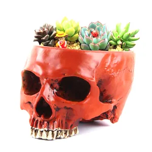 Red skull-shaped succulent flower pot with decorative miniature figurines