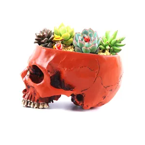 Detailed macro view of a red resin skull planter with vibrant green succulents
