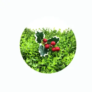 Close-up of artificial Christmas holly berries with green leaves on a grass background.
