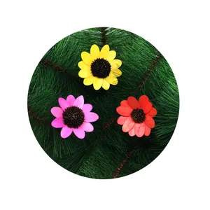 Three colorful wooden sunflowers on green pine needles for handmade DIY Christmas crafts