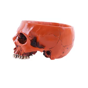 Close-up side view of a realistic orange skull shaped resin planter for Halloween decor