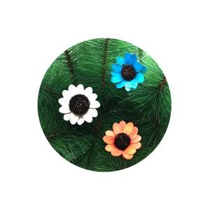 Close-up of colorful wooden sunflower decorations on green pine needle background