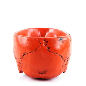 Close-up detail of a bright orange Halloween skull planter featuring black bone sutures