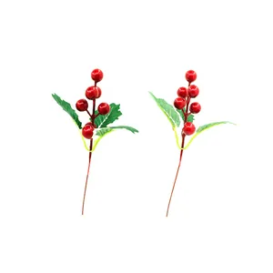 Detail view of two artificial Christmas red berry stems with green leaves on white