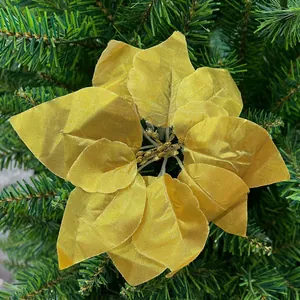 Close-up detail of a decorative golden artificial poinsettia flower on a green Christmas tree