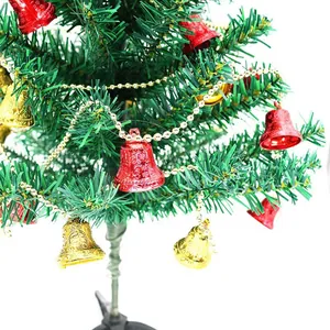 Close-up of red and gold Christmas bell garland hanging on a green tree branch