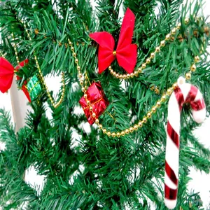 Close-up of festive Christmas tree ornaments with golden beaded garland and red bows.