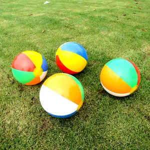Set of four vibrant six-color inflatable beach balls placed on a lush green lawn outdoor