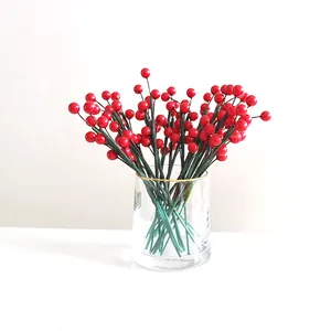 Détail de branches de baies rouges de Noël dans un vase en verre à bord doré