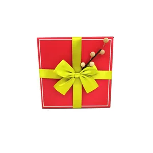 Boîte cadeau de Noël rouge avec nœud vert citron et détail de branche de baies décorative