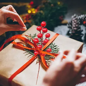 Detail van een decoratieve kunstmatige rode bessensteel op een kerstcadeauverpakking
