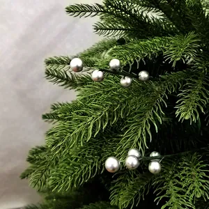 Gros plan de baies de Noël argentées et d'aiguilles de pin artificielles pour décorations DIY.