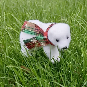 Detailed view of white flocked Christmas polar bear figurine with red plaid scarf on grass