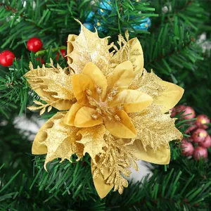 Nahaufnahme einer glitzernden goldenen Weihnachtsblume an einem grünen Tannenzweig.