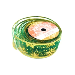 Dettaglio ravvicinato di nastro natalizio in rete verde con eleganti fiocchi di neve dorati.
