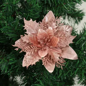 Detailansicht einer dekorativen roségoldenen Glitzer-Weihnachtsblume am Tannenbaum