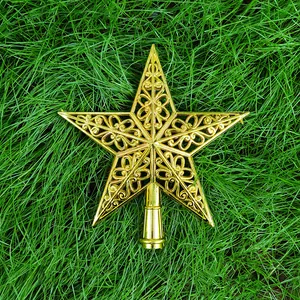 Vue détaillée d'une étoile de cime de sapin de Noël dorée et évidée sur de l'herbe verte