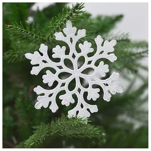 Glittery white acrylic snowflake ornament hanging on a lush Christmas tree branch.