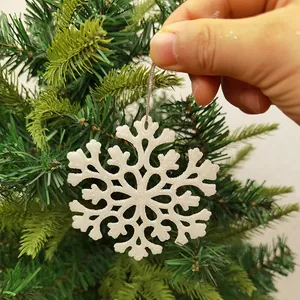 Close-up detail of a white glittery acrylic snowflake ornament hung on a Christmas tree