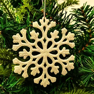 Close-up of a white glittery acrylic snowflake ornament on a Christmas tree